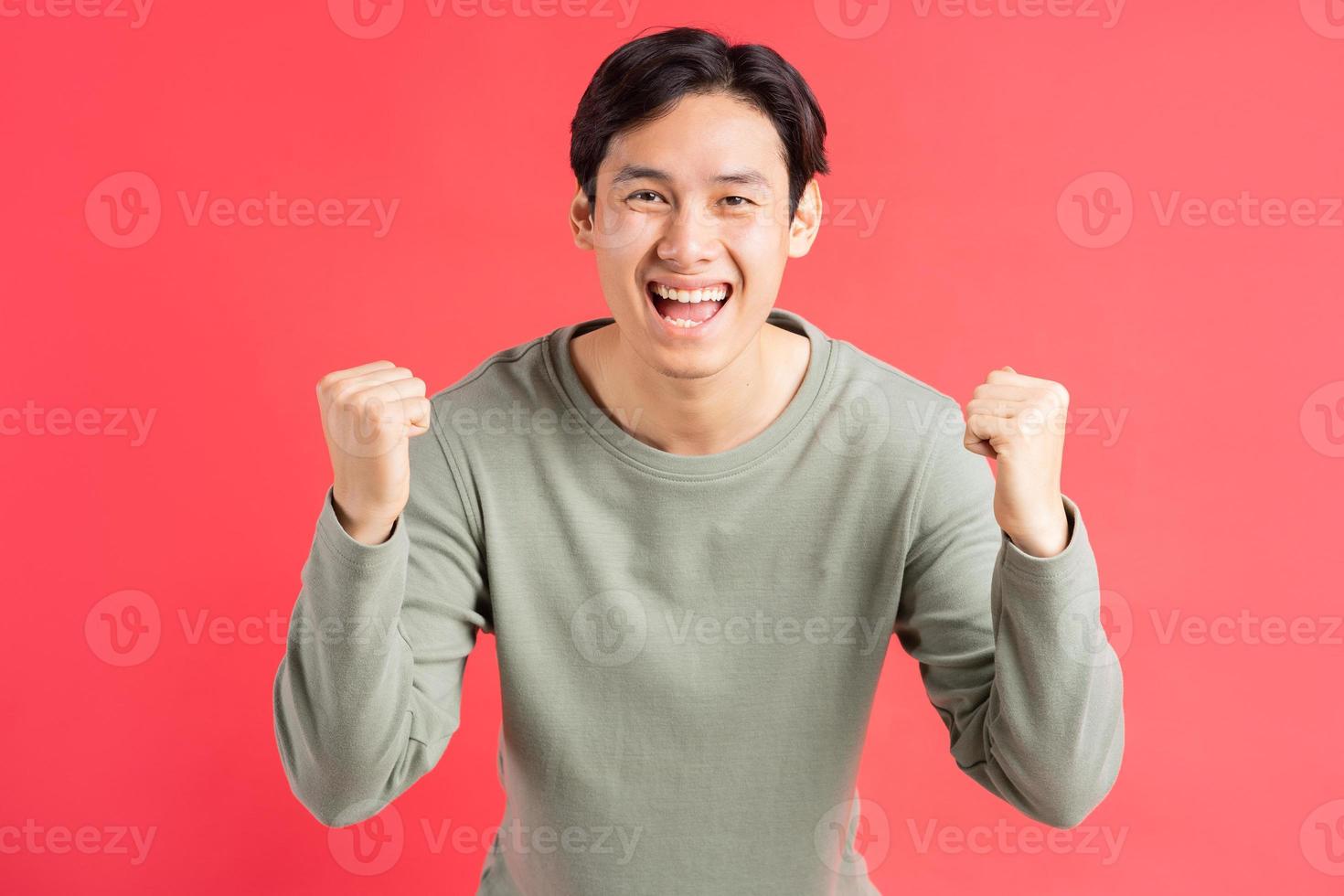 una foto di un bell'uomo asiatico che usa la mano per esprimere i suoi sentimenti di vittoria