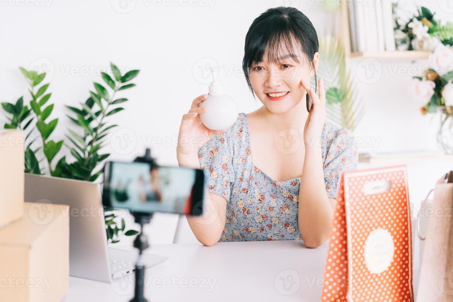 donna d'affari asiatica utilizza gli smartphone per trasmettere in streaming la vendita di cosmetici su siti di social network e siti di e-commerce. foto