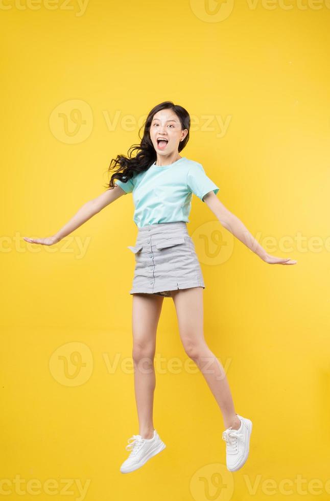 giovane ragazza asiatica che salta sul baclground giallo foto