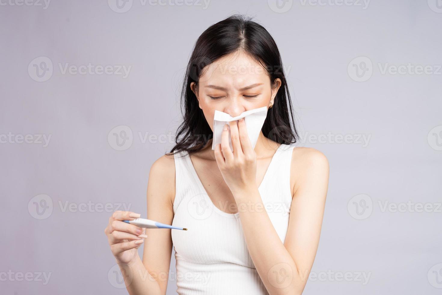 la donna asiatica misura la temperatura corporea quando ha il raffreddore foto