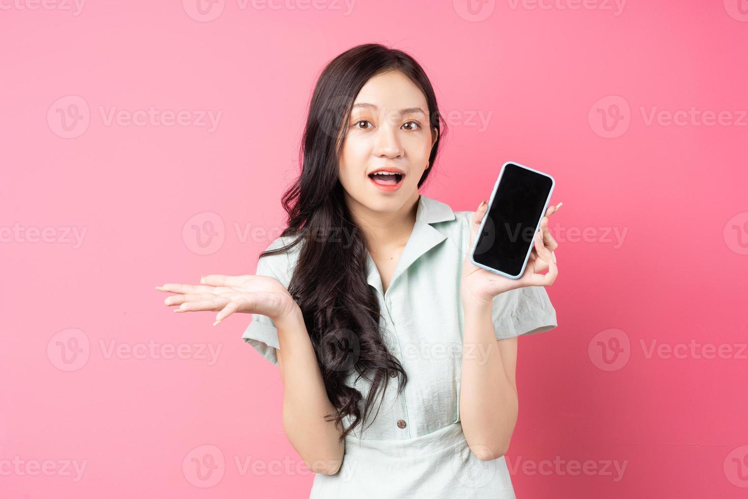 giovane donna asiatica che tiene il telefono in mano con sguardo sorpreso foto