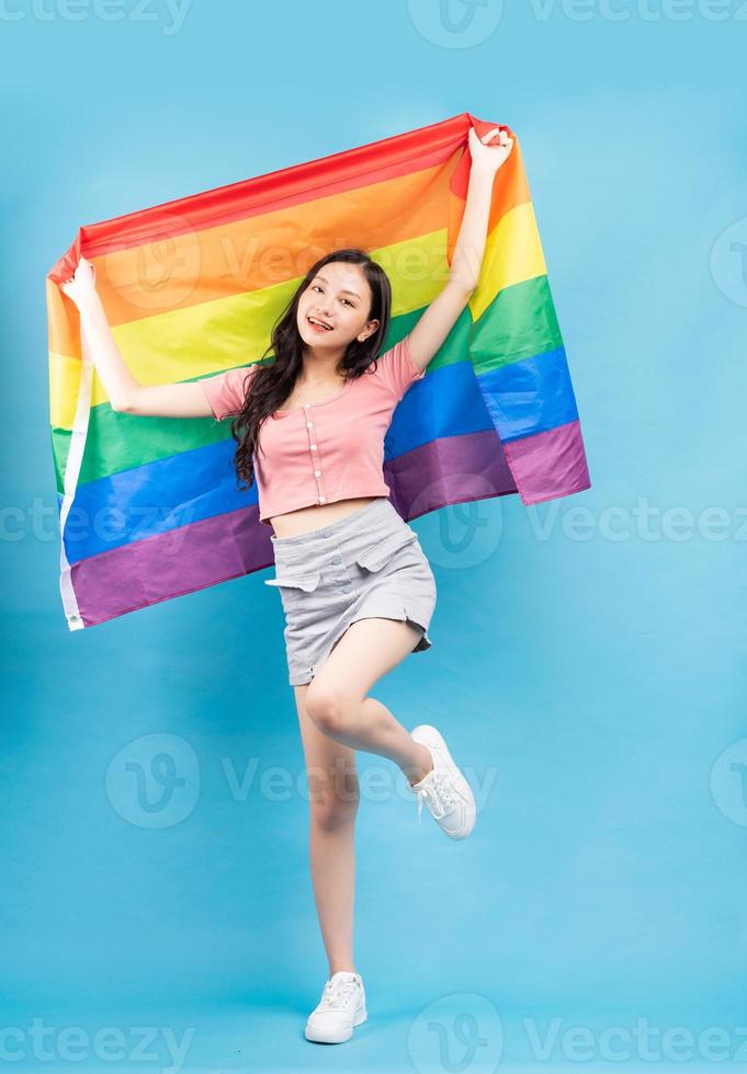 giovane donna asiatica che tiene la bandiera arcobaleno per sostenere la comunità lgbtq foto