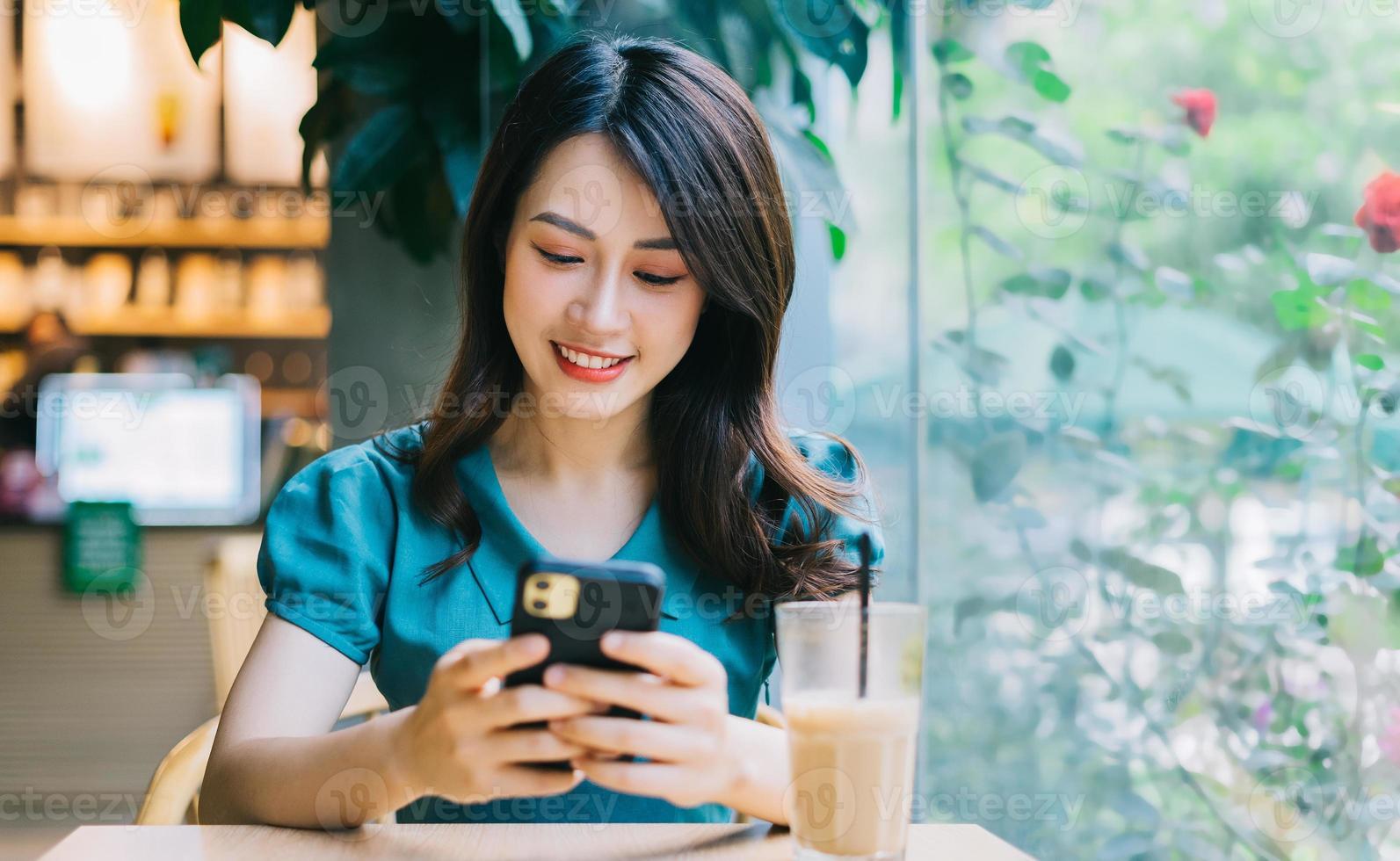 giovane donna asiatica che sorride mentre usa lo smartphone foto