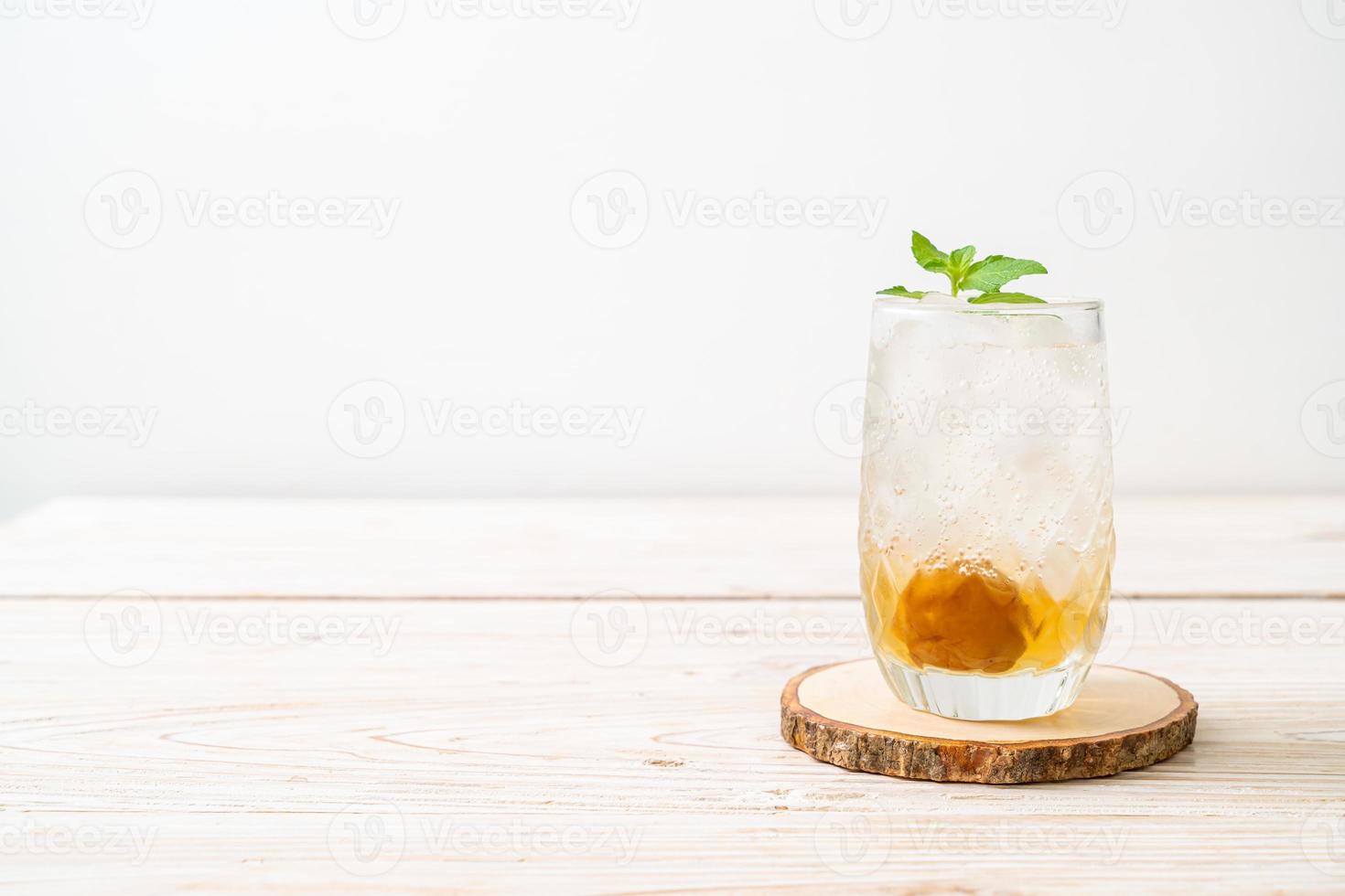 succo di prugna ghiacciato con soda e menta piperita sul tavolo di legno - bevanda rinfrescante foto