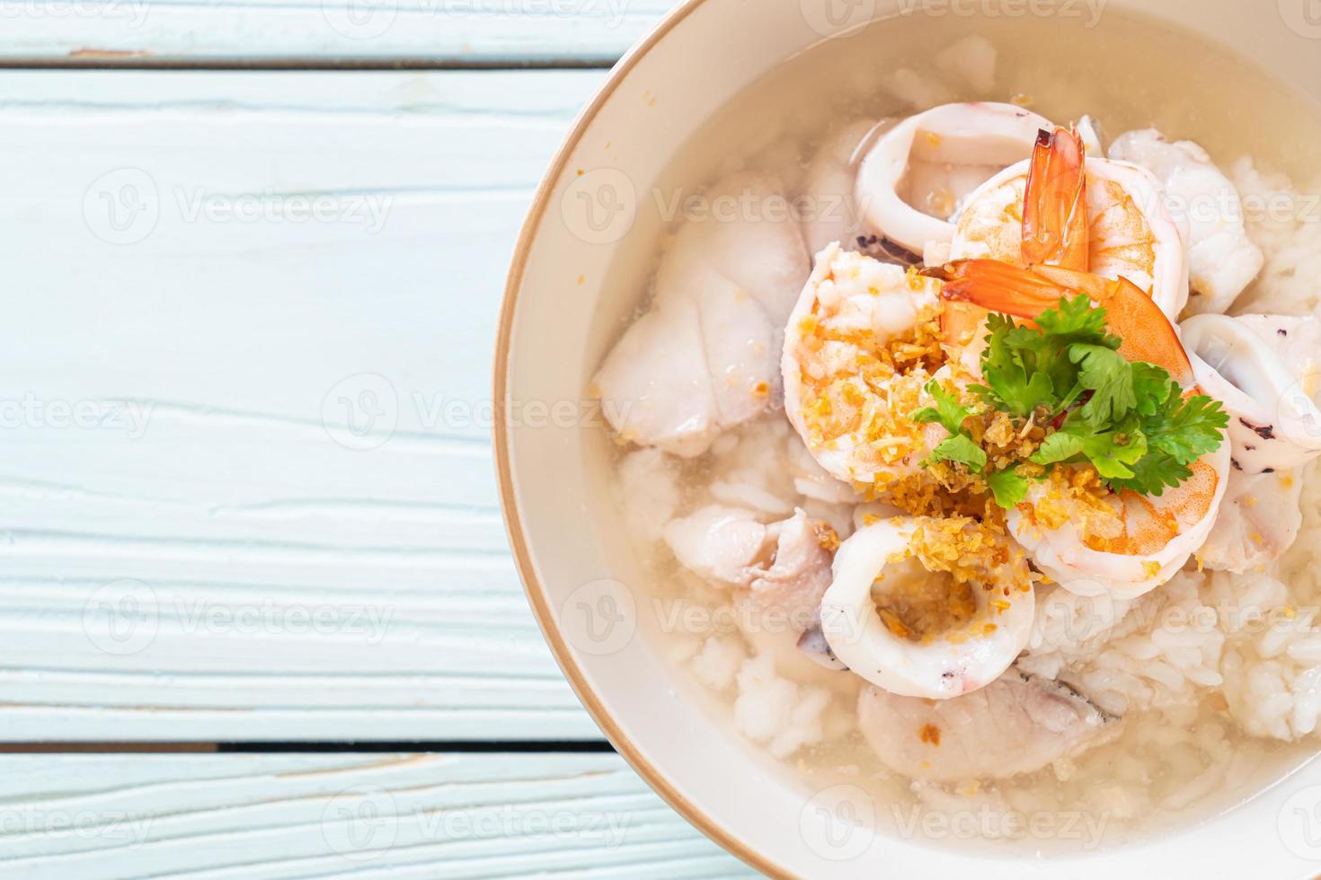 zuppa di porridge o riso bollito con frutti di mare di gamberi, calamari e pesce in una ciotola foto