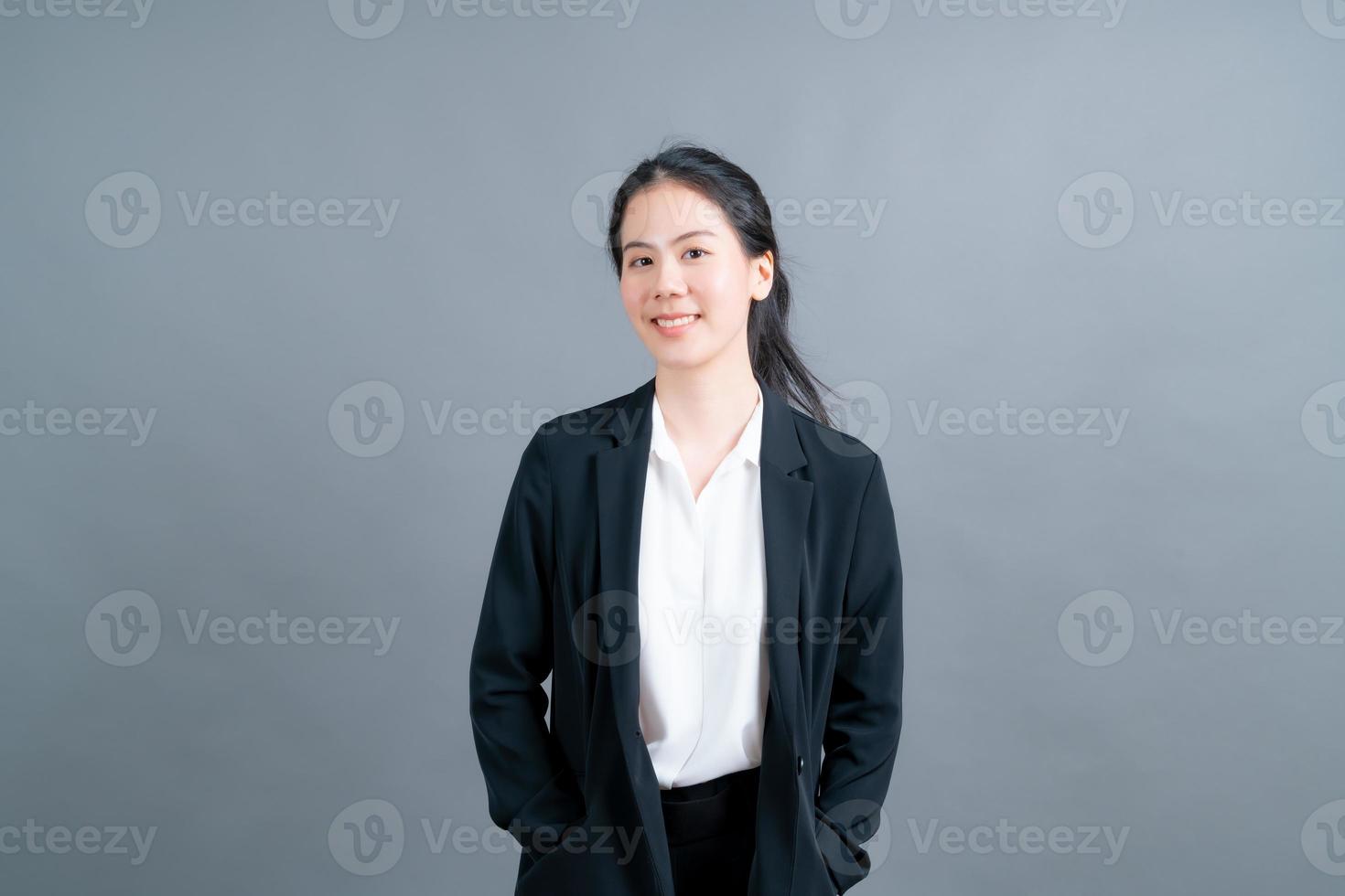 donna asiatica felice con la faccia felice in abiti da ufficio su sfondo grigio foto