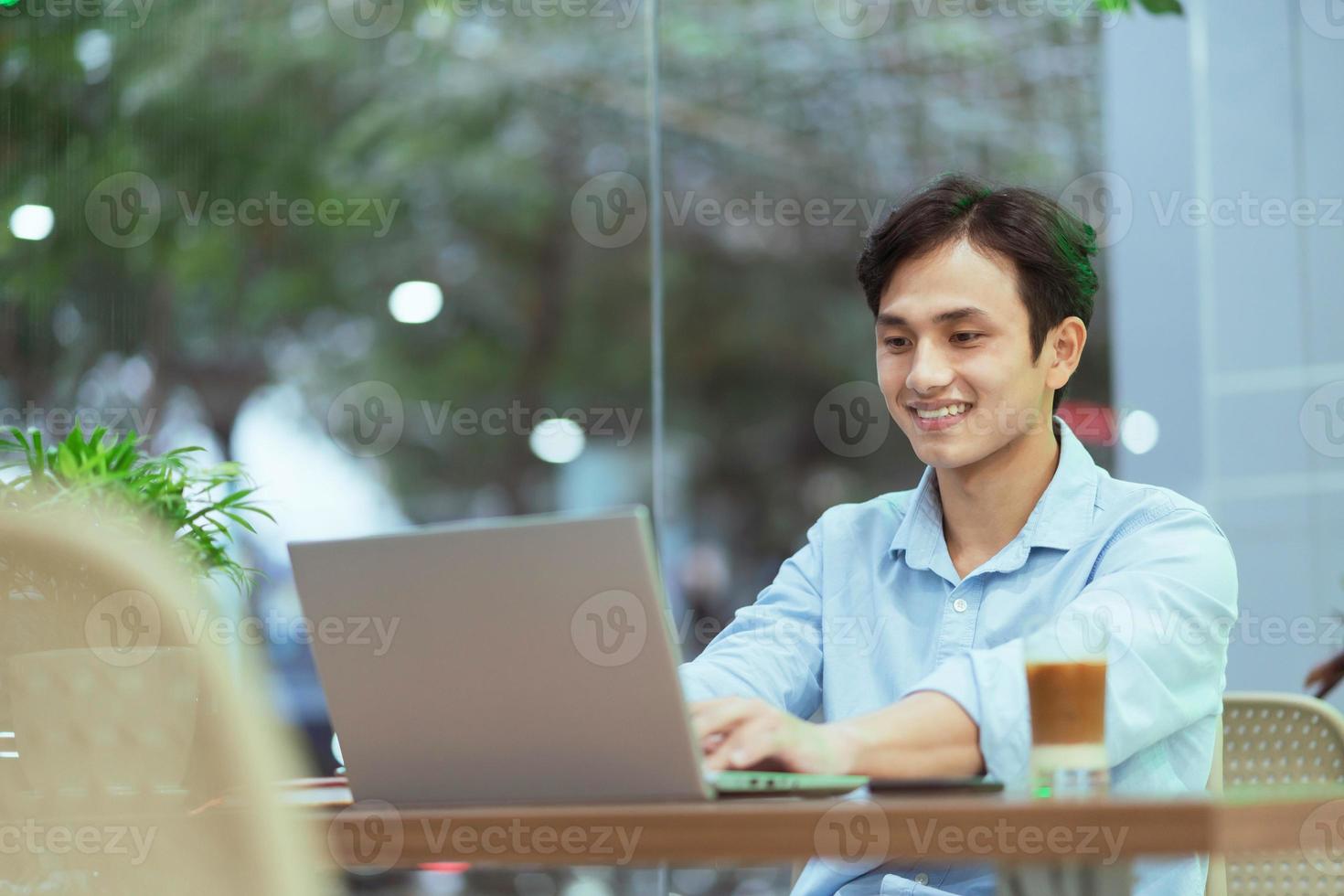 uomo asiatico seduto a lavorare da solo in un bar foto