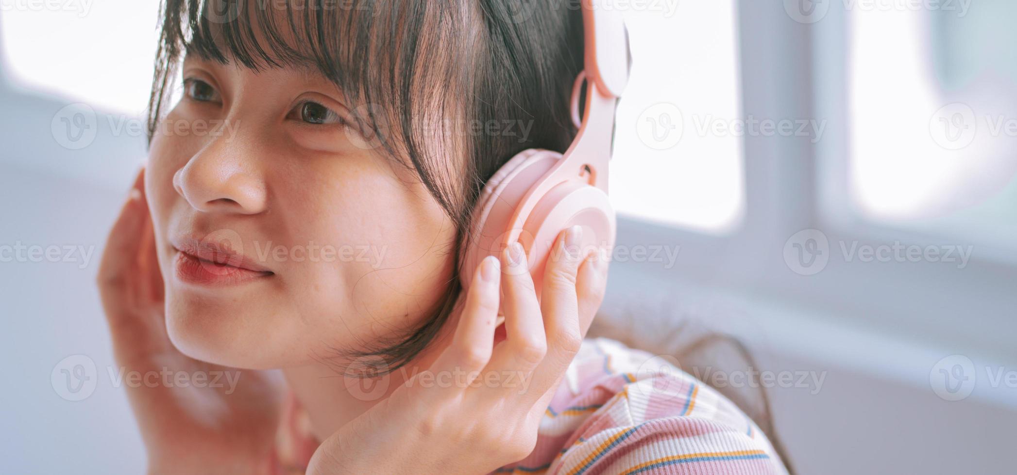 giovane donna asiatica che usa le cuffie wireless per ascoltare la musica foto