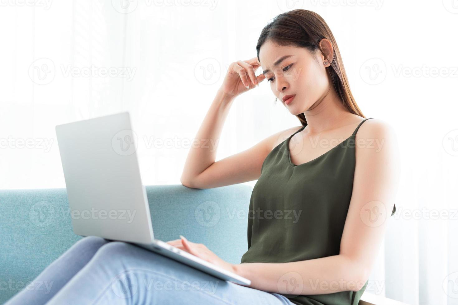 la donna asiatica sta usando il laptop con un'espressione preoccupata foto