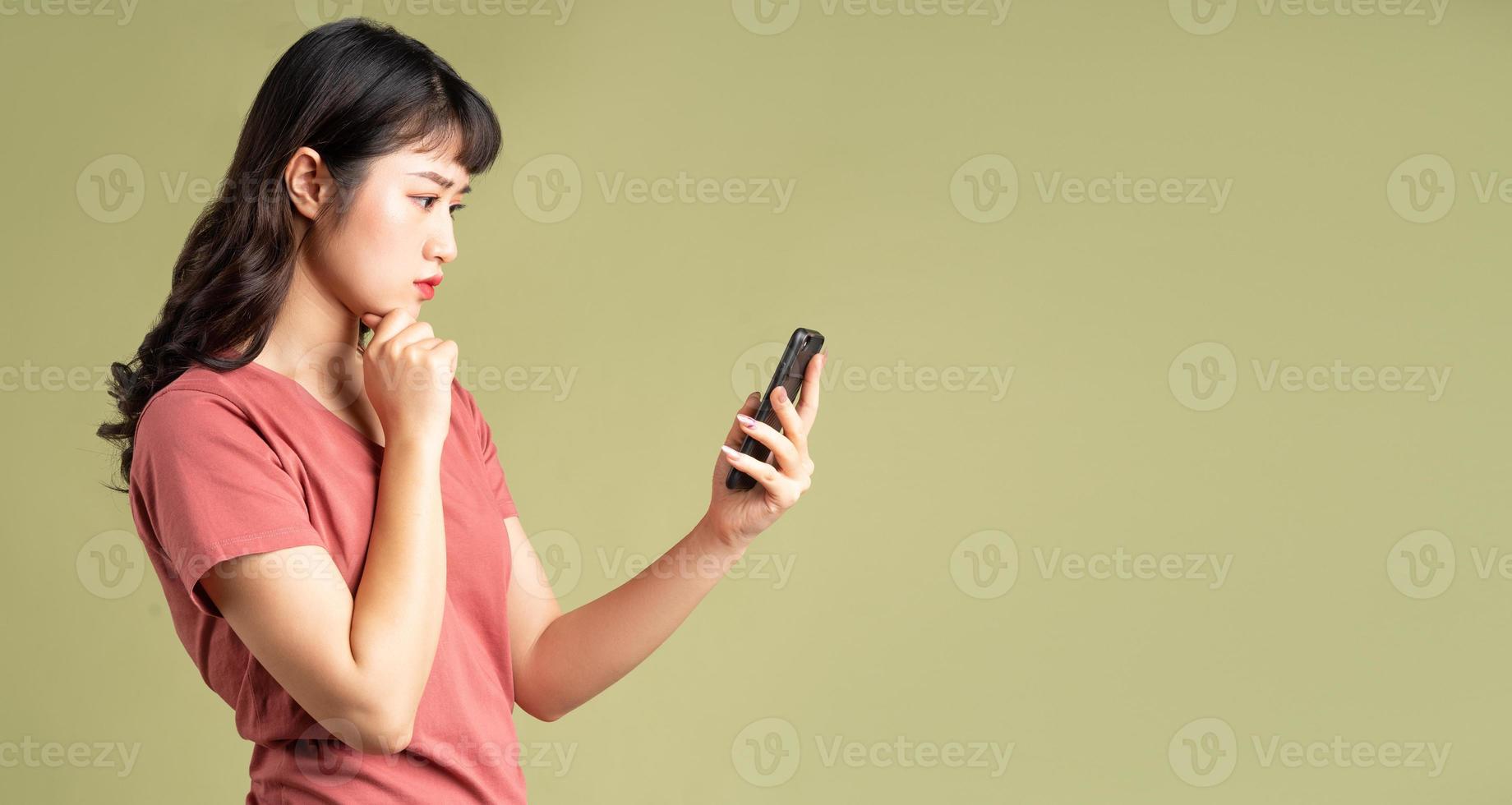 la donna asiatica stava fissando il telefono con un'espressione pensierosa foto