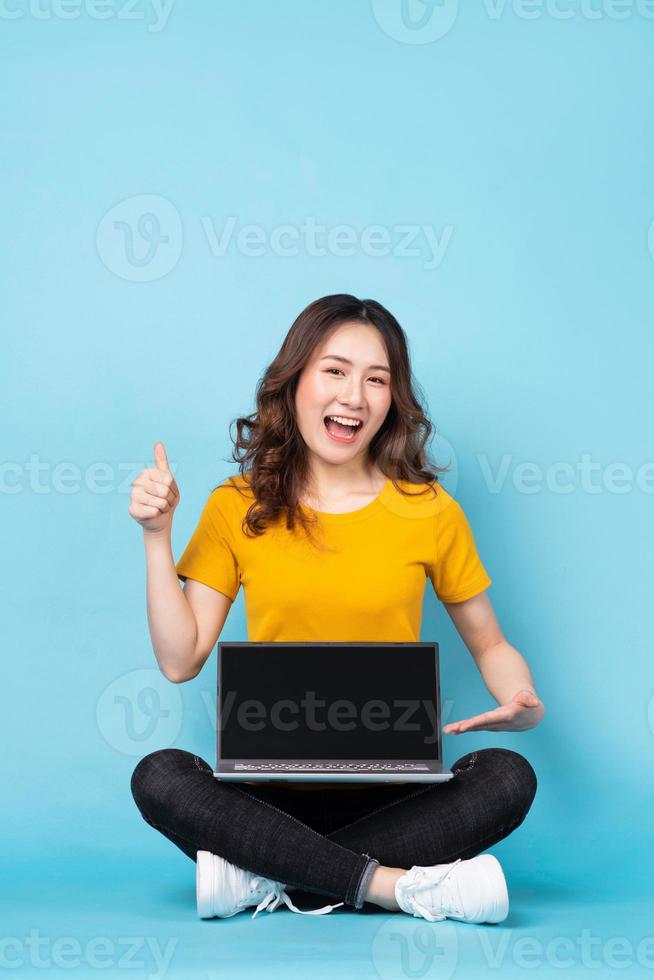 giovane ragazza seduta utilizzando laptop con espressioni e gesti sullo sfondo foto