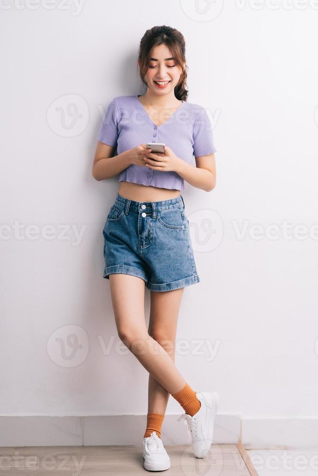 giovane donna asiatica che utilizza smartphone su sfondo bianco foto