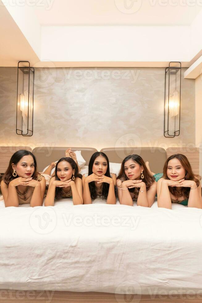 un' gruppo di asiatico donne siamo dire bugie su bianca materassi con loro amici nel un' Hotel foto