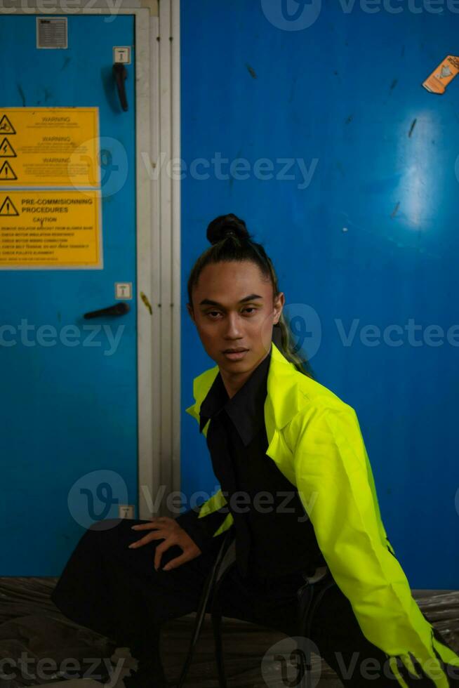 un asiatico uomo con esotico pelle squat nel davanti di un' blu sfondo foto