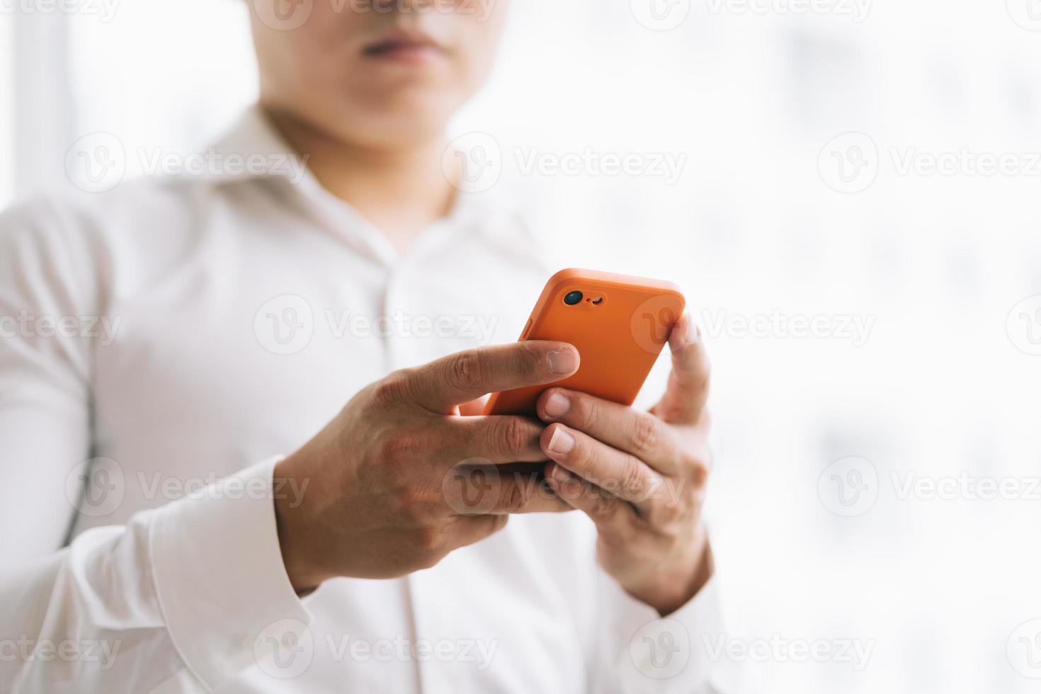 uomo d'affari asiatico che utilizza smartphone vicino alla finestra foto