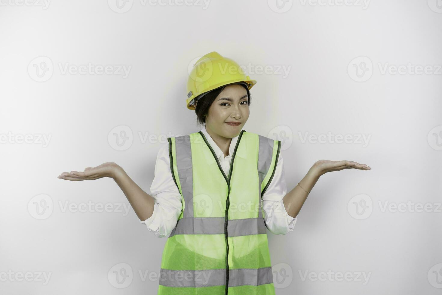 un' riflessivo giovane donna lavoro duro e faticoso indossare sicurezza casco e veste è confuso fra scelte accanto suo, isolato di bianca sfondo. lavoro giorno concetto. foto