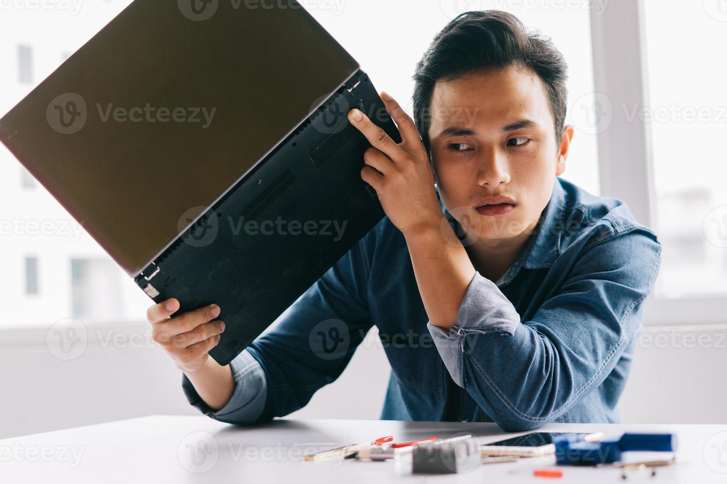 l'uomo asiatico stava tirando fuori un computer rotto per ripararlo foto