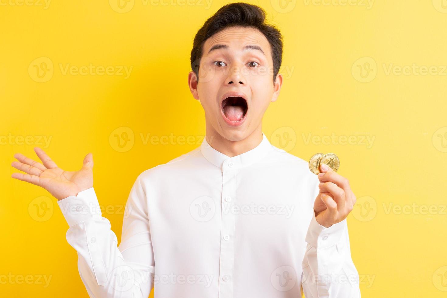 uomo d'affari asiatico che tiene bitcoin in mano wite faccia felice foto