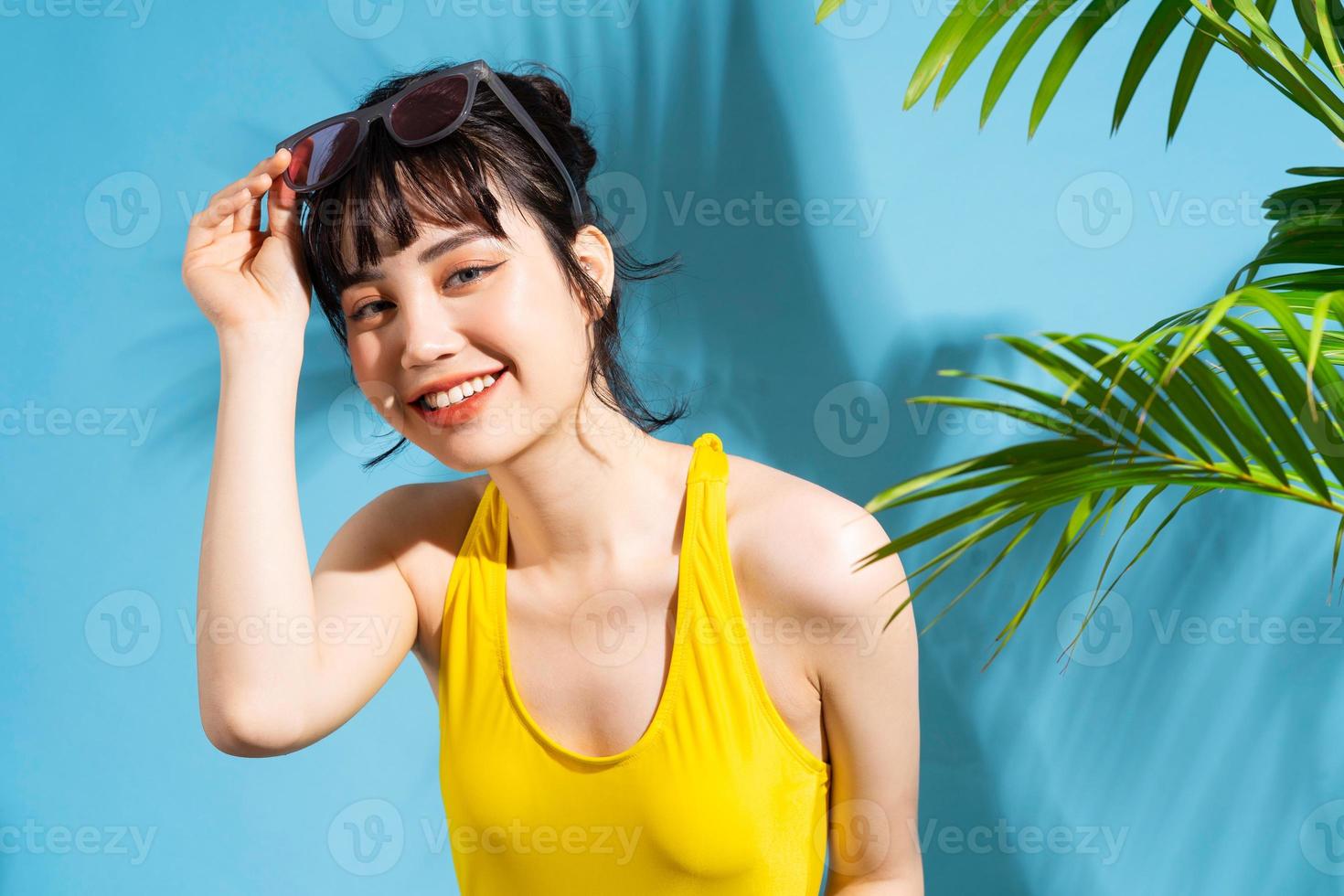 bella donna asiatica che indossa una tuta gialla su sfondo blu e, concetto estivo foto