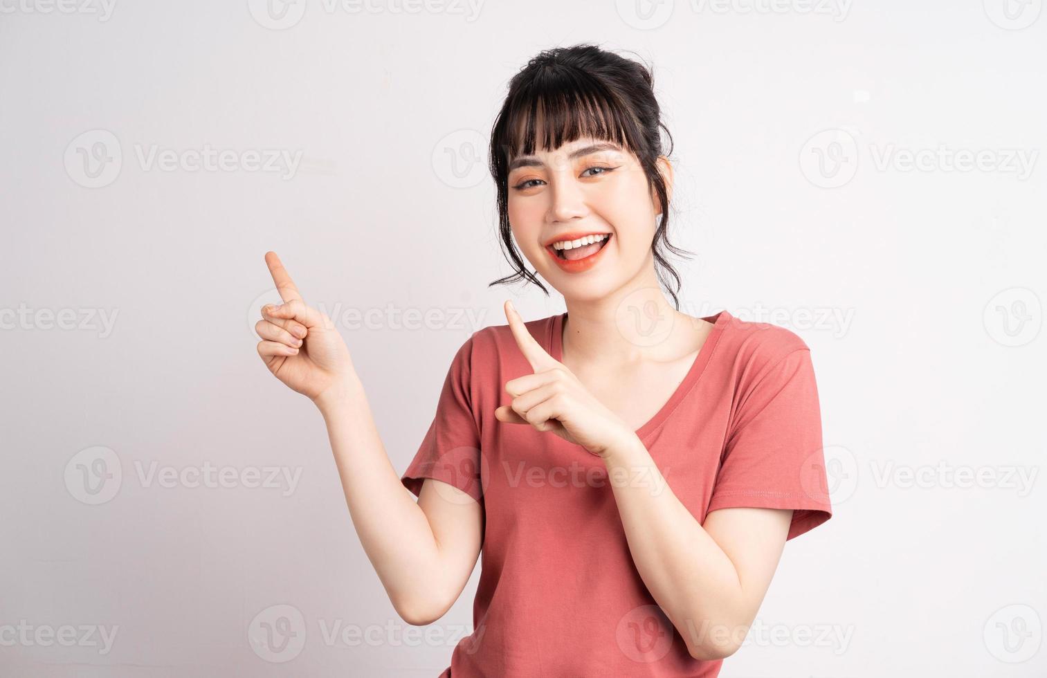 giovane donna asiatica in posa su sfondo bianco, usando il dito per indicare e mostrare, gesto della mano foto