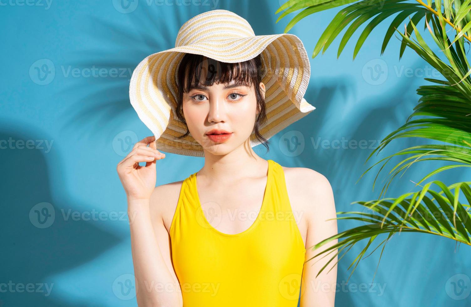 bella donna asiatica che indossa una tuta gialla su sfondo blu e, concetto estivo foto