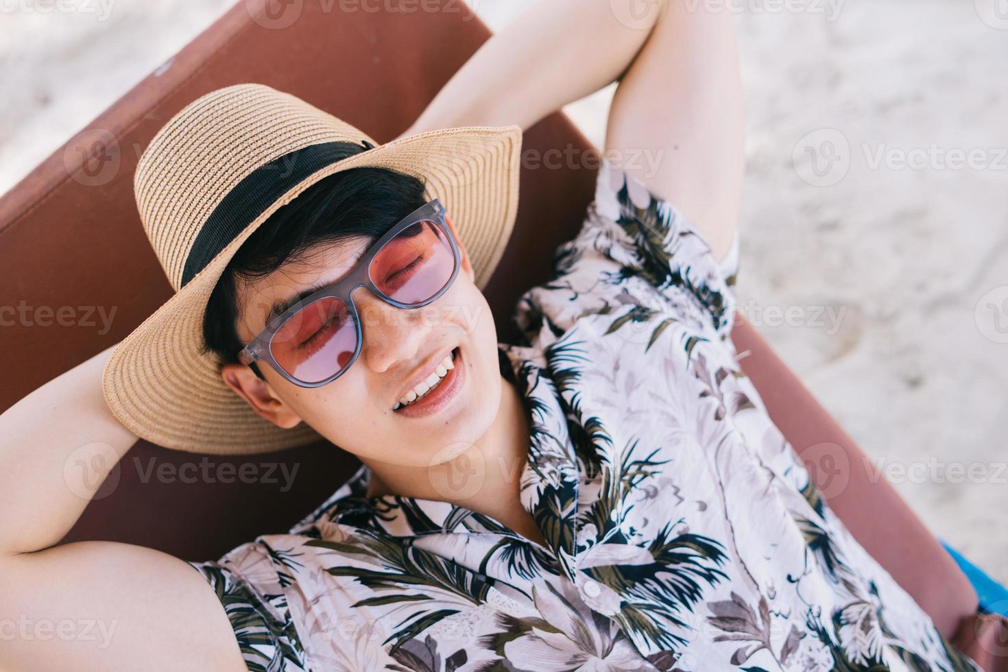 uomo asiatico sdraiato a riposo sulla spiaggia foto