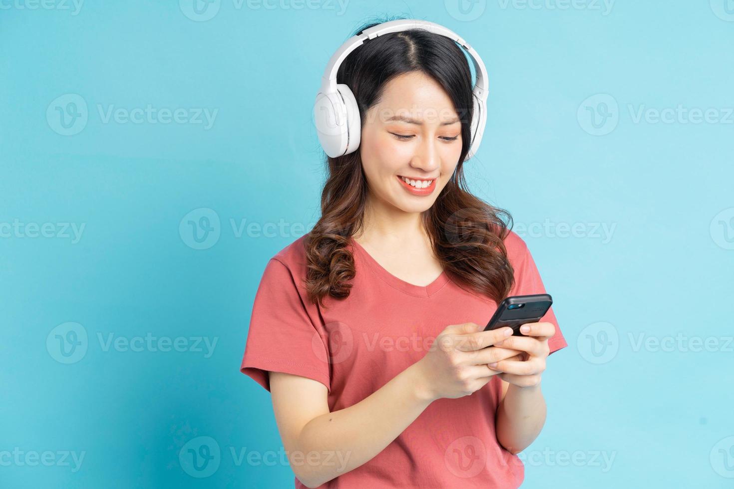 la bella donna asiatica sta usando l'elettricità mentre ascolta la musica con le cuffie wireless bianche foto