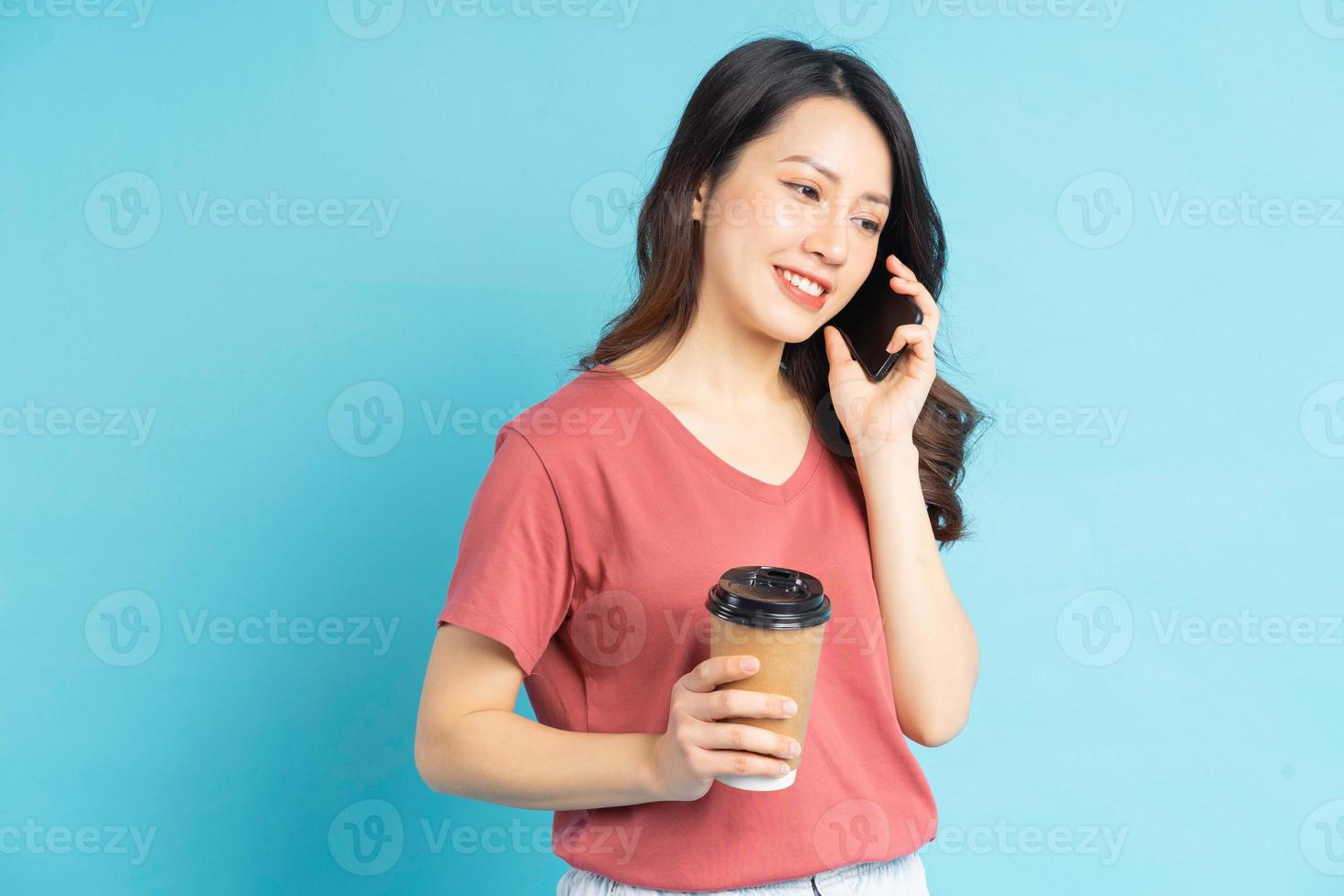 bella donna asiatica che tiene in mano una tazza di caffè e fa una telefonata foto