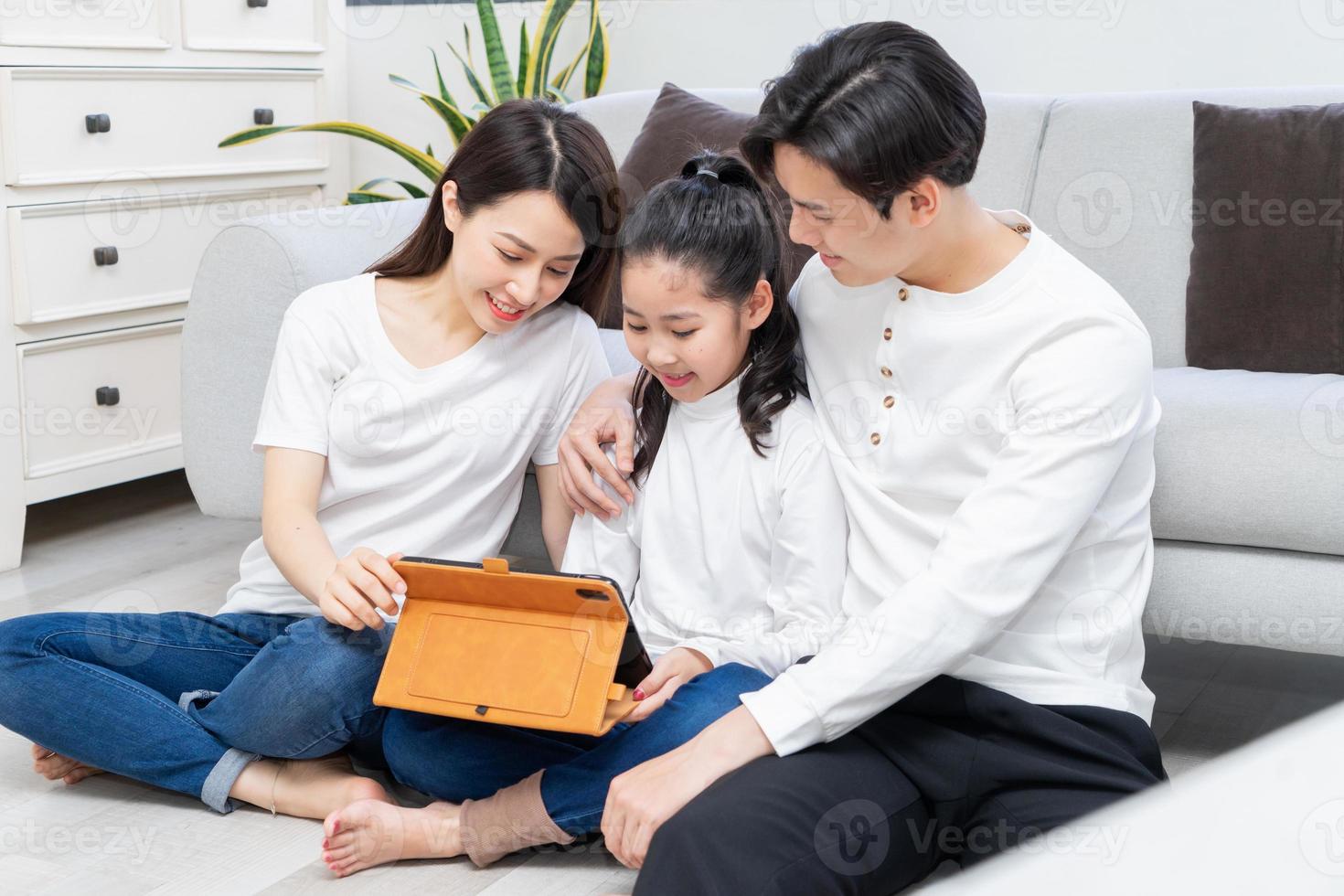 i genitori asiatici stanno guidando la loro figlia a usare il tablet foto