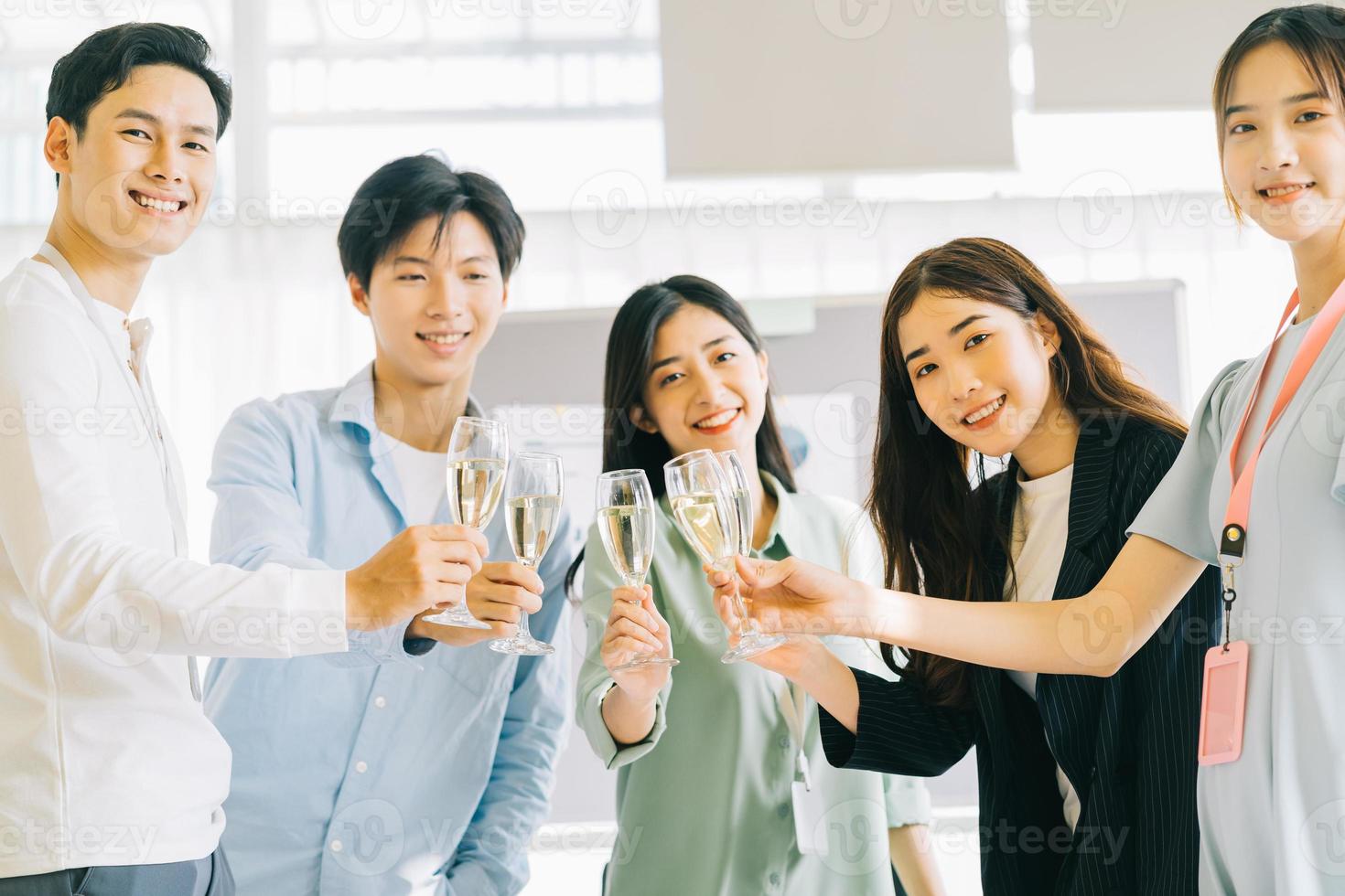 gli uomini d'affari asiatici brindano ai loro bicchieri celebrando i risultati foto