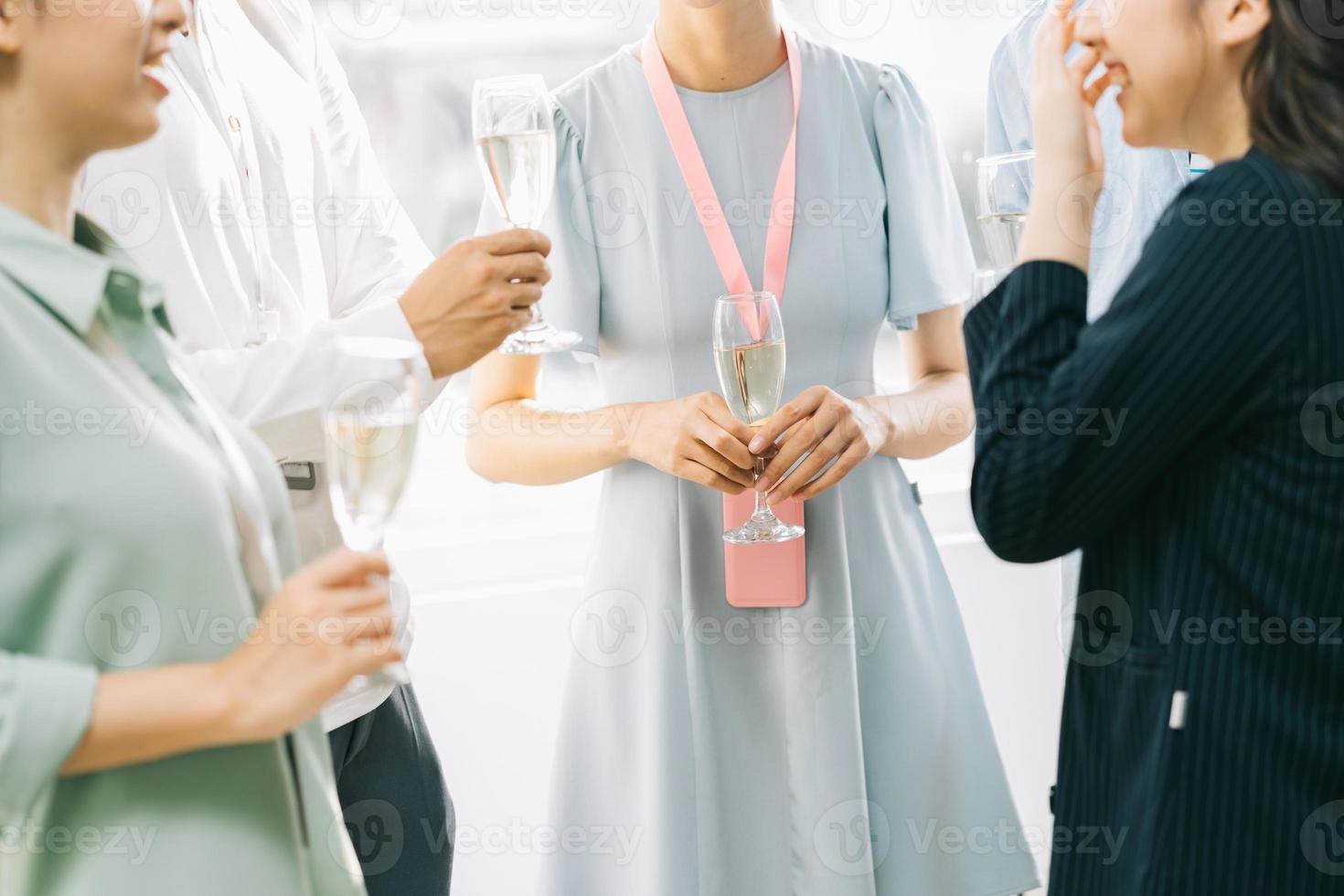 gli uomini d'affari asiatici del gruppo stanno brindando insieme e chiacchierando a una festa aziendale foto