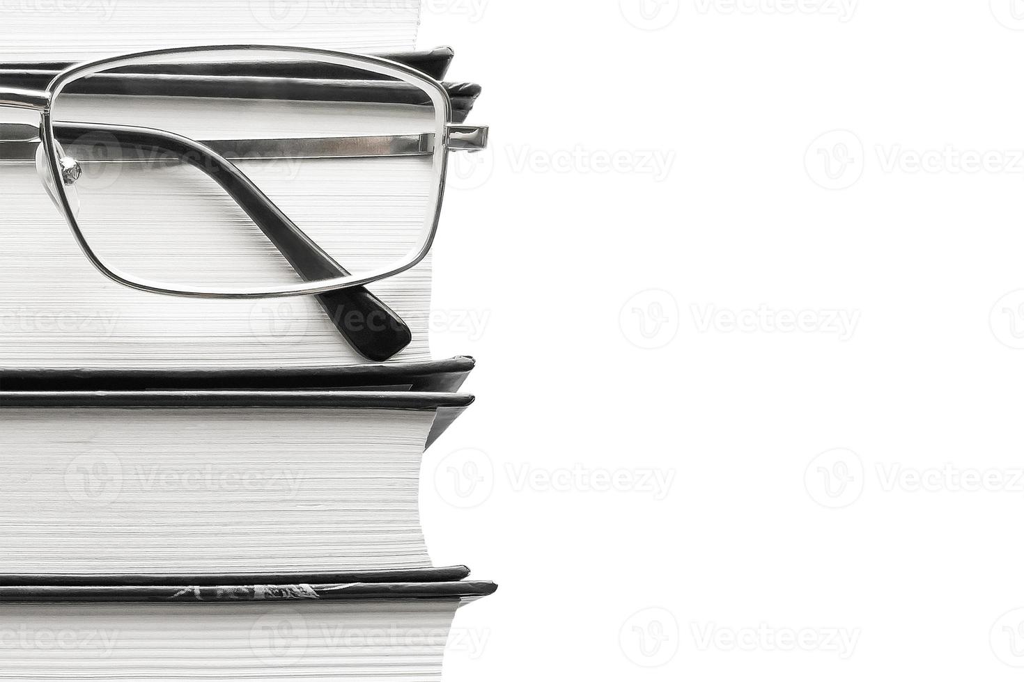 occhiali e libri spessi su sfondo bianco foto