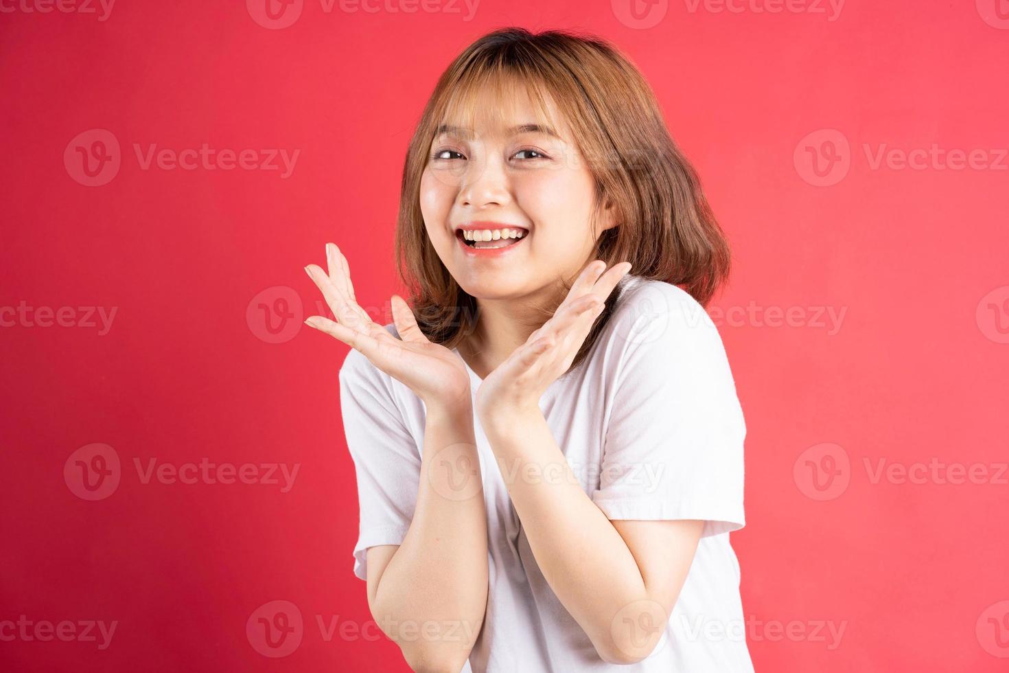 giovane ragazza asiatica con gesti ed espressioni allegri sullo sfondo foto
