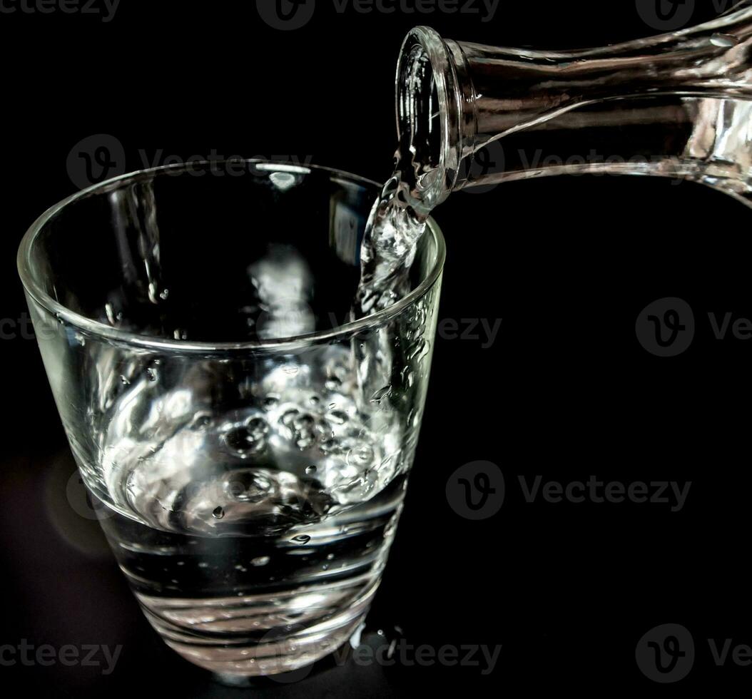 versare l'acqua dalla bottiglia nel bicchiere foto