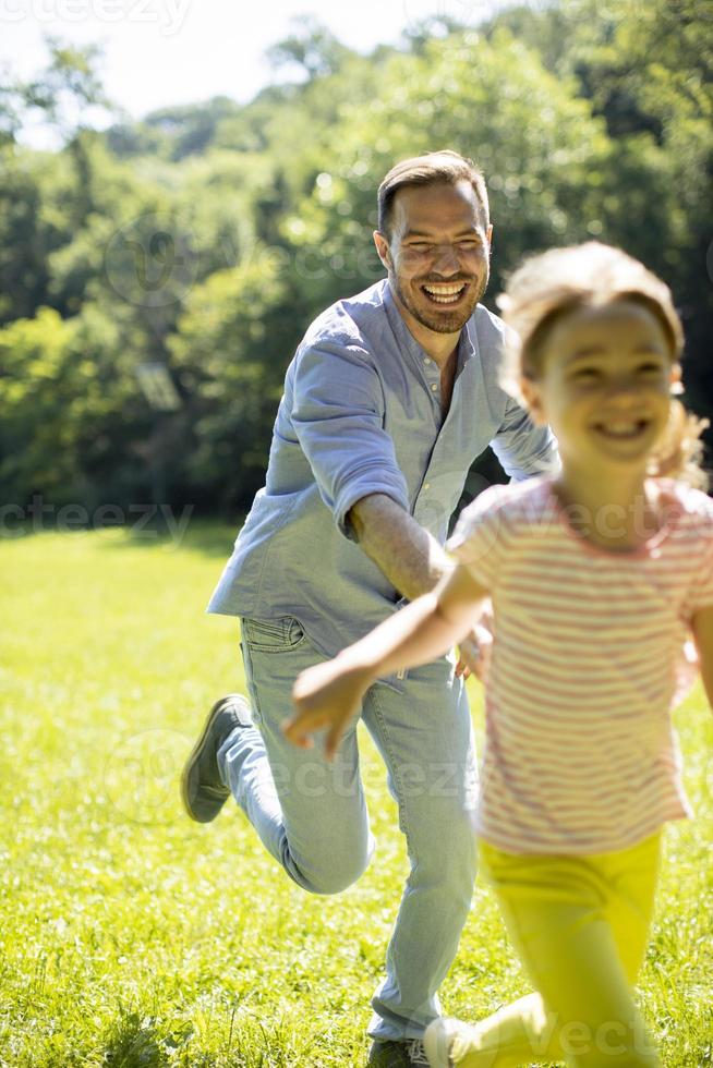 padre che insegue la sua piccola figlia mentre gioca nel parco foto