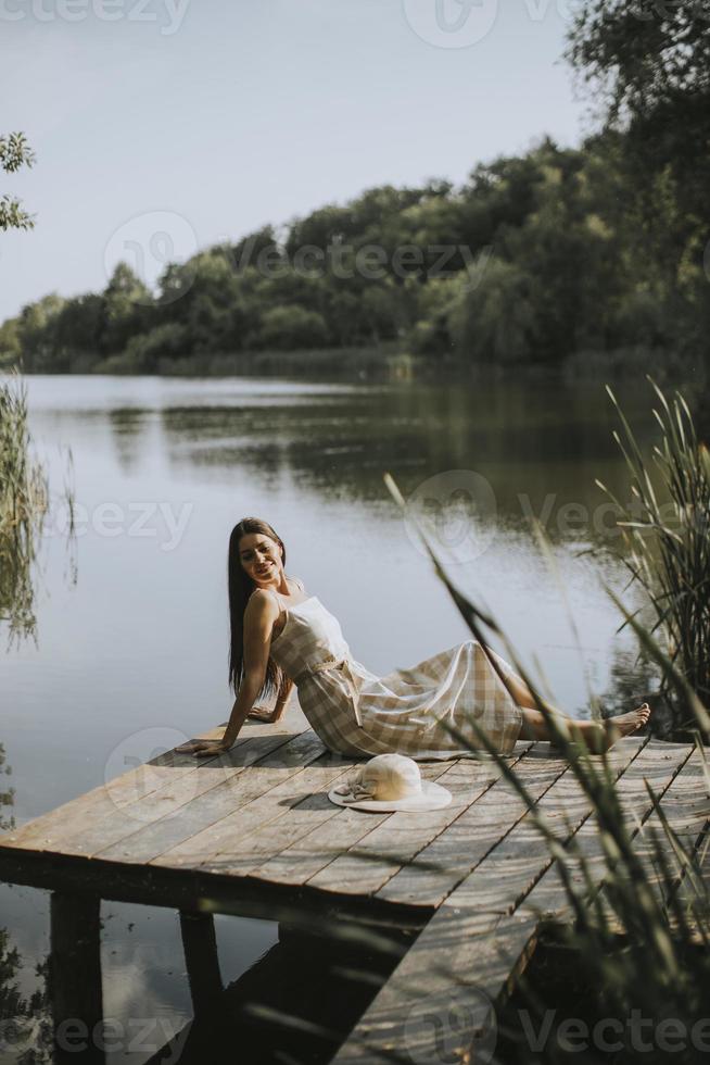 rilassante giovane donna sul molo di legno al lago foto