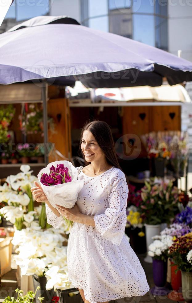 giovane donna che compra fiori al mercato dei fiori foto