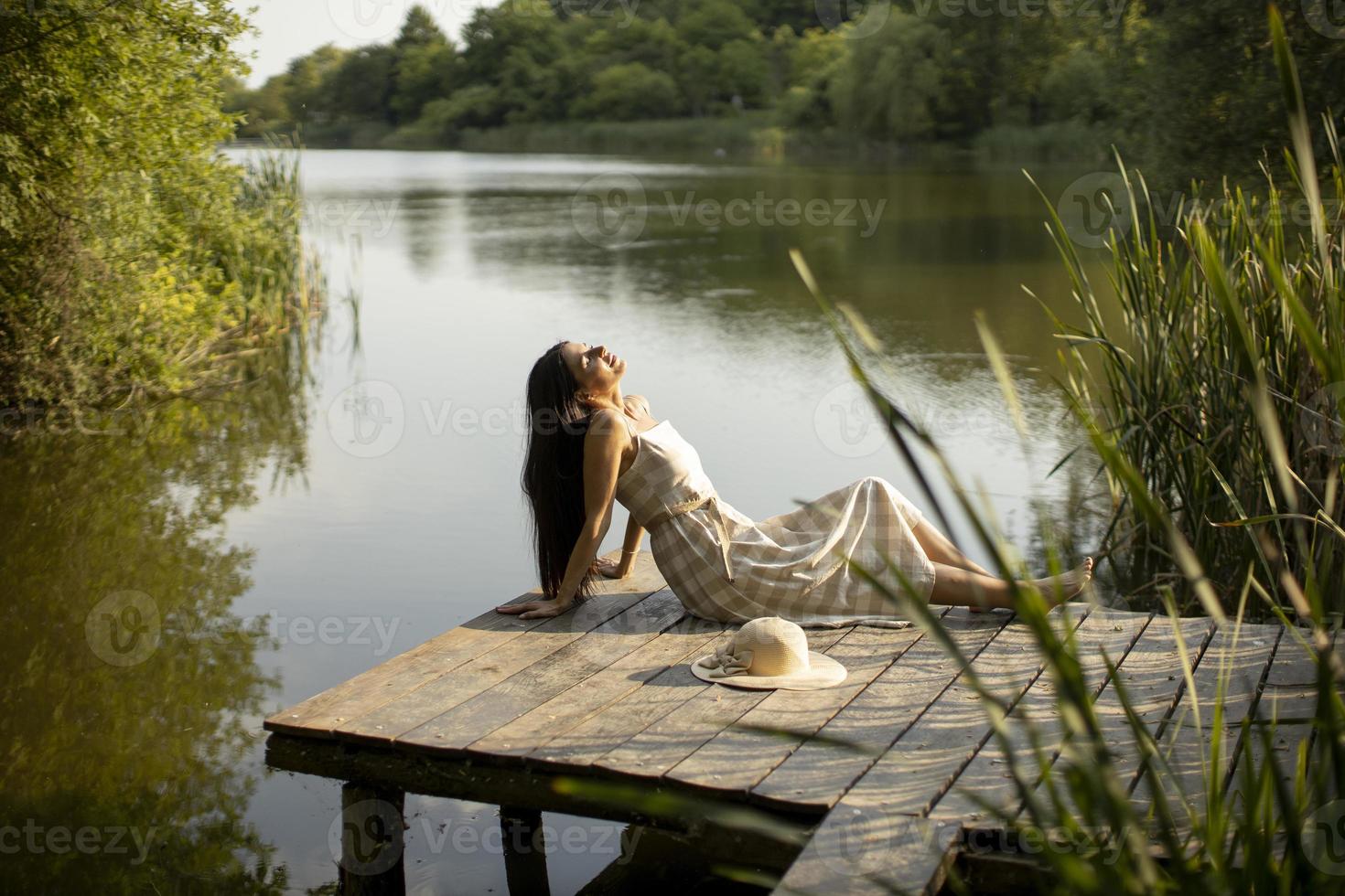 rilassante giovane donna sul molo di legno al lago foto