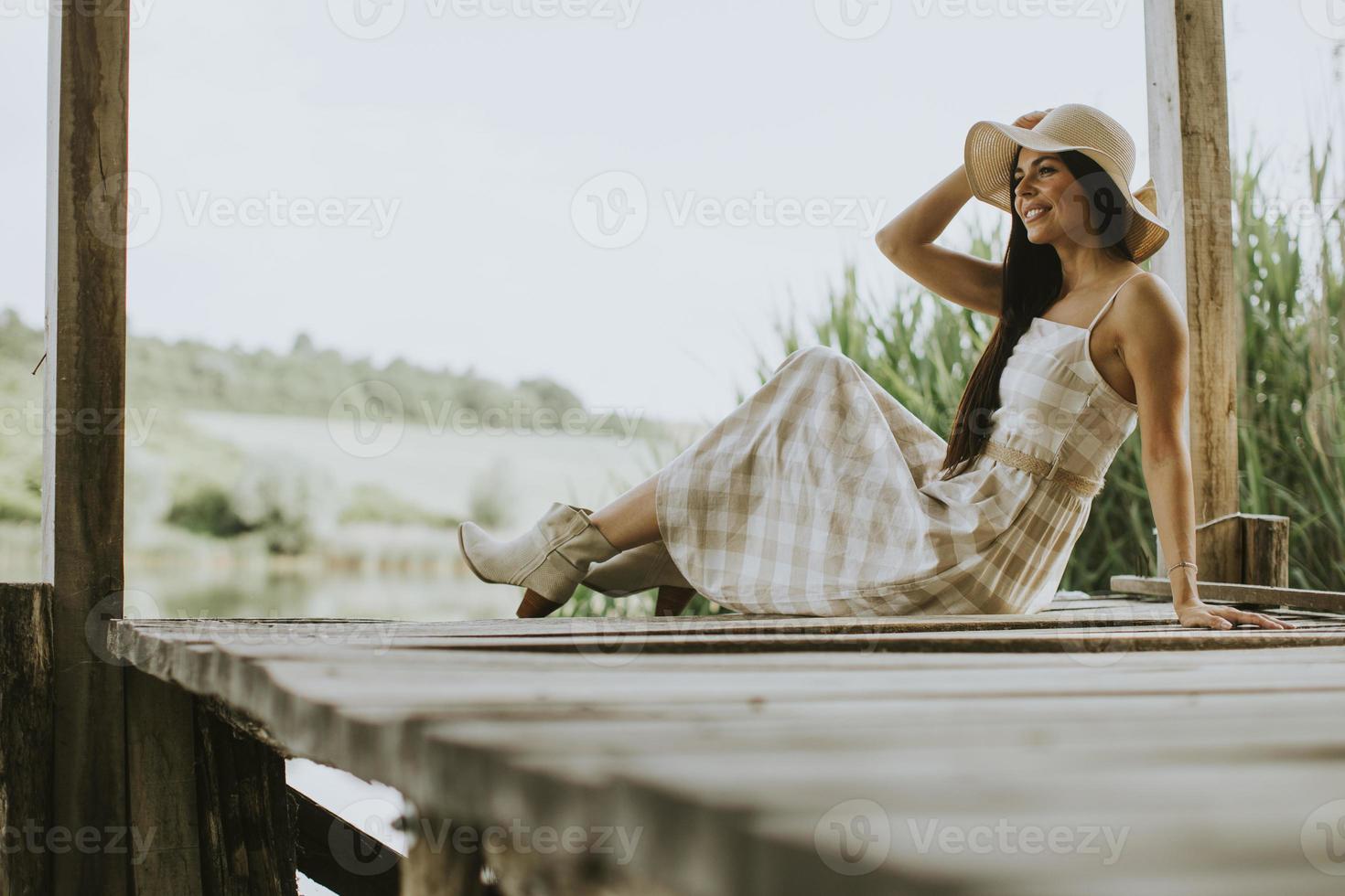 rilassante giovane donna sul molo di legno al lago foto