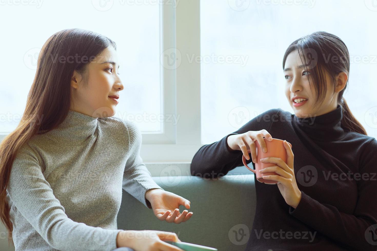 donne asiatiche che chiacchierano vicino alla finestra foto