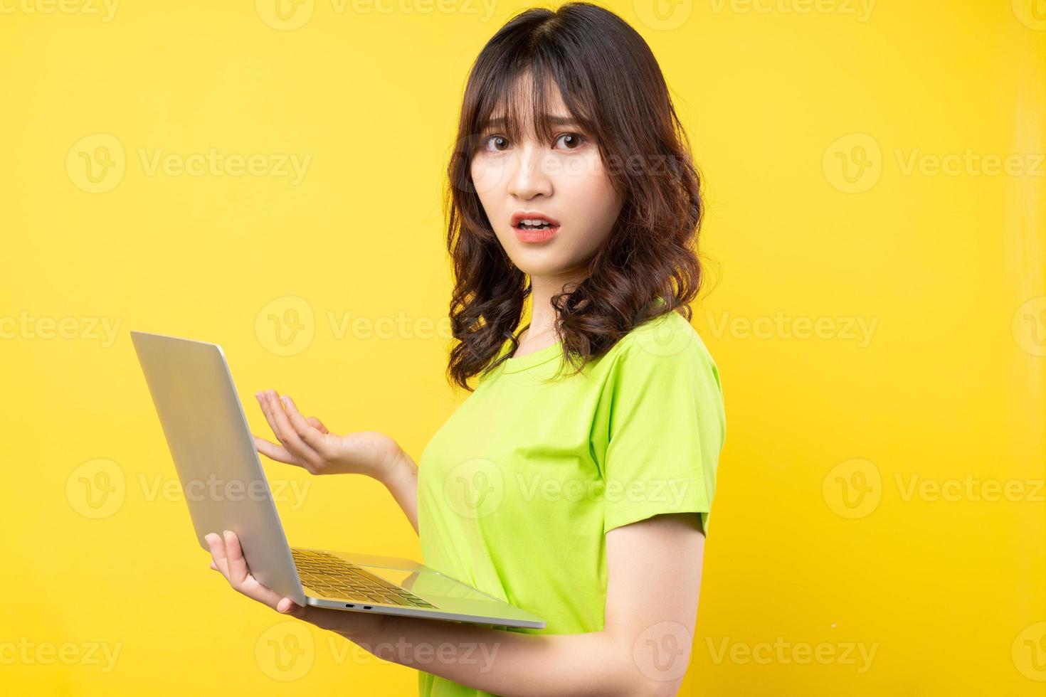 giovane donna asiatica che utilizza laptop su sfondo giallo yellow foto