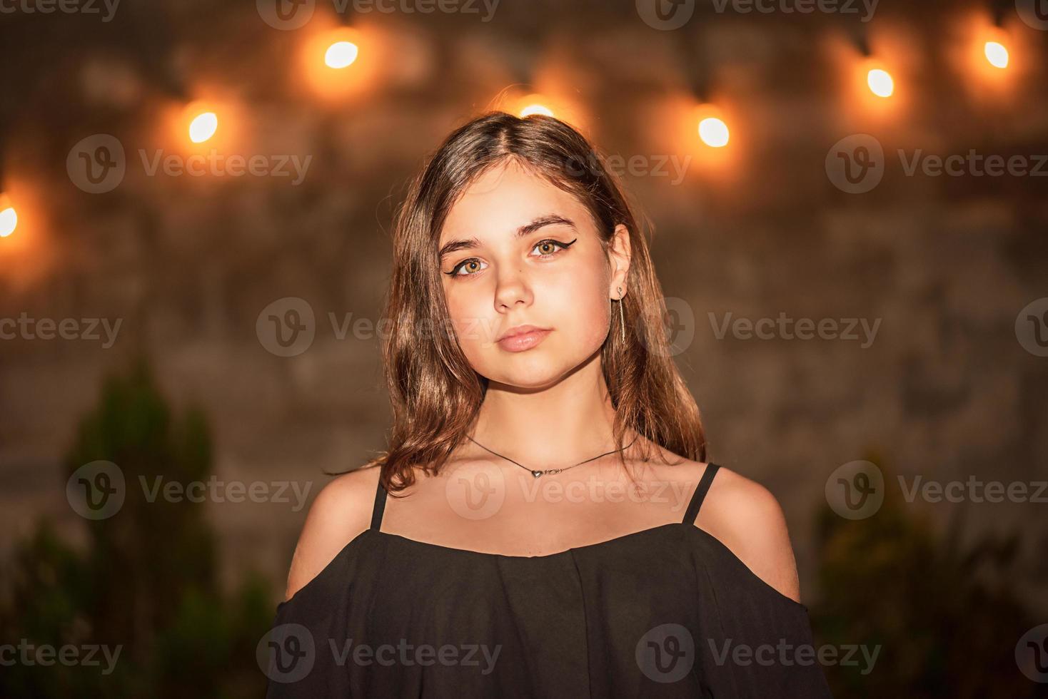 giovane bella modella. bruna guarda nella telecamera. adolescente in un abito nero la sera. foto