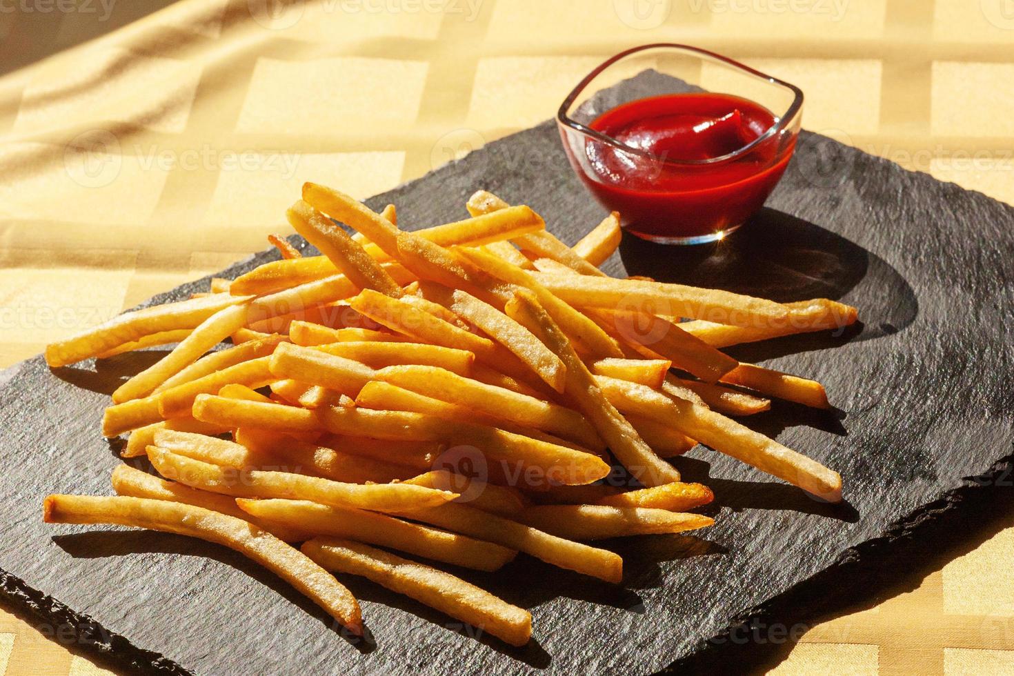 patatine fritte con salsa di pomodoro su ardesia nera. fritto, patatine foto