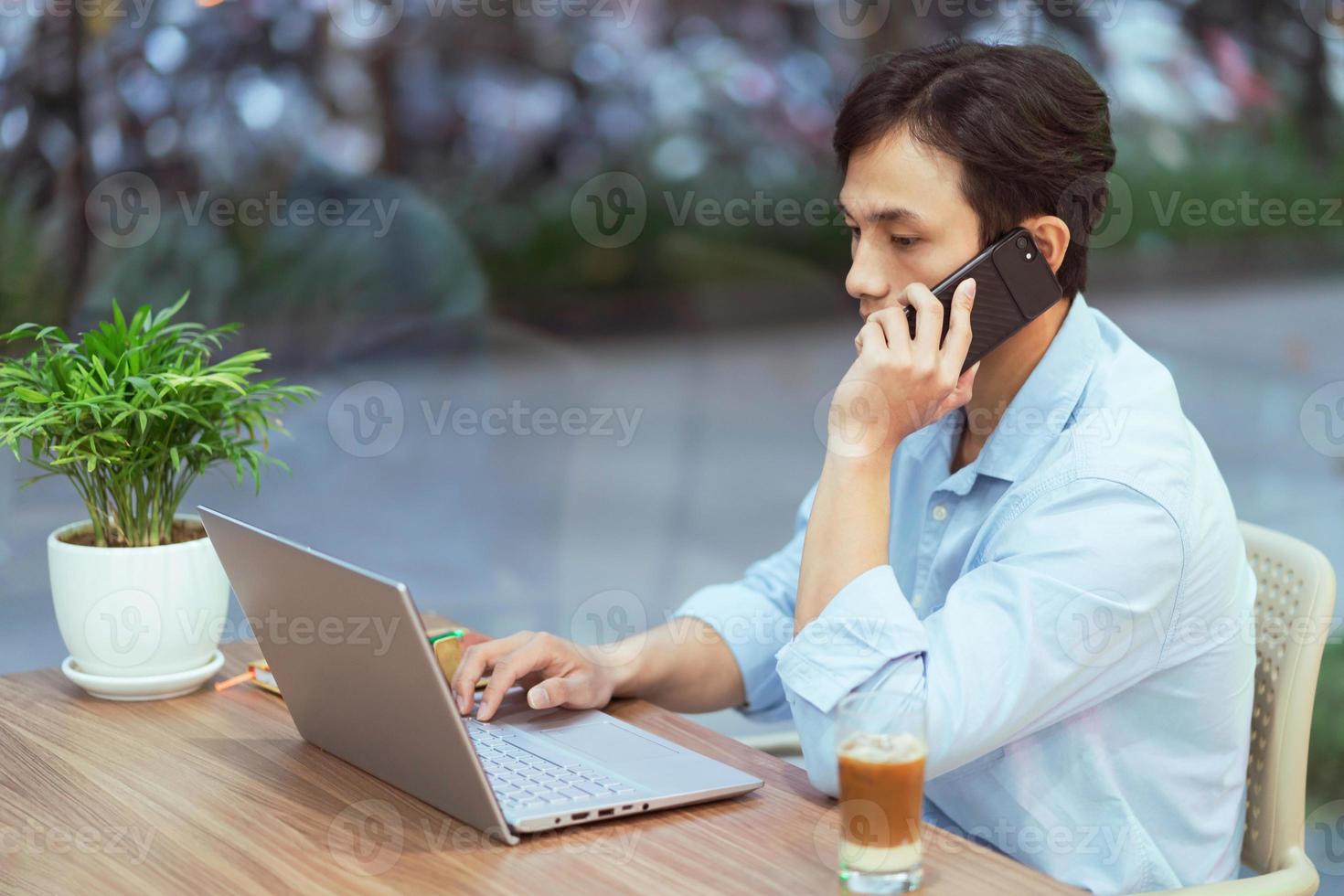 uomo asiatico con laptop e telefono foto