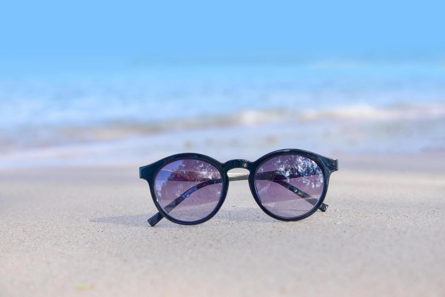 occhiali da sole sulla spiaggia in mare e sullo sfondo del tramonto vacanze estive foto