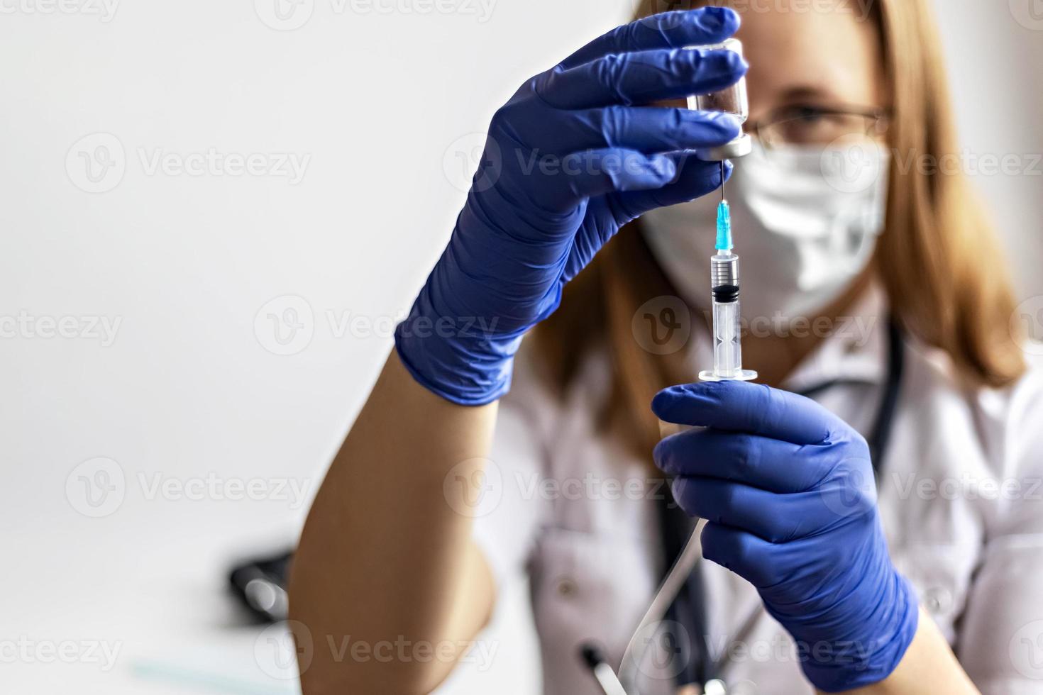 una dottoressa che indossa una maschera medica aspira il vaccino contro il coronavirus in una siringa presso la clinica. il concetto di vaccinazione, immunizzazione, prevenzione contro covid-19. foto