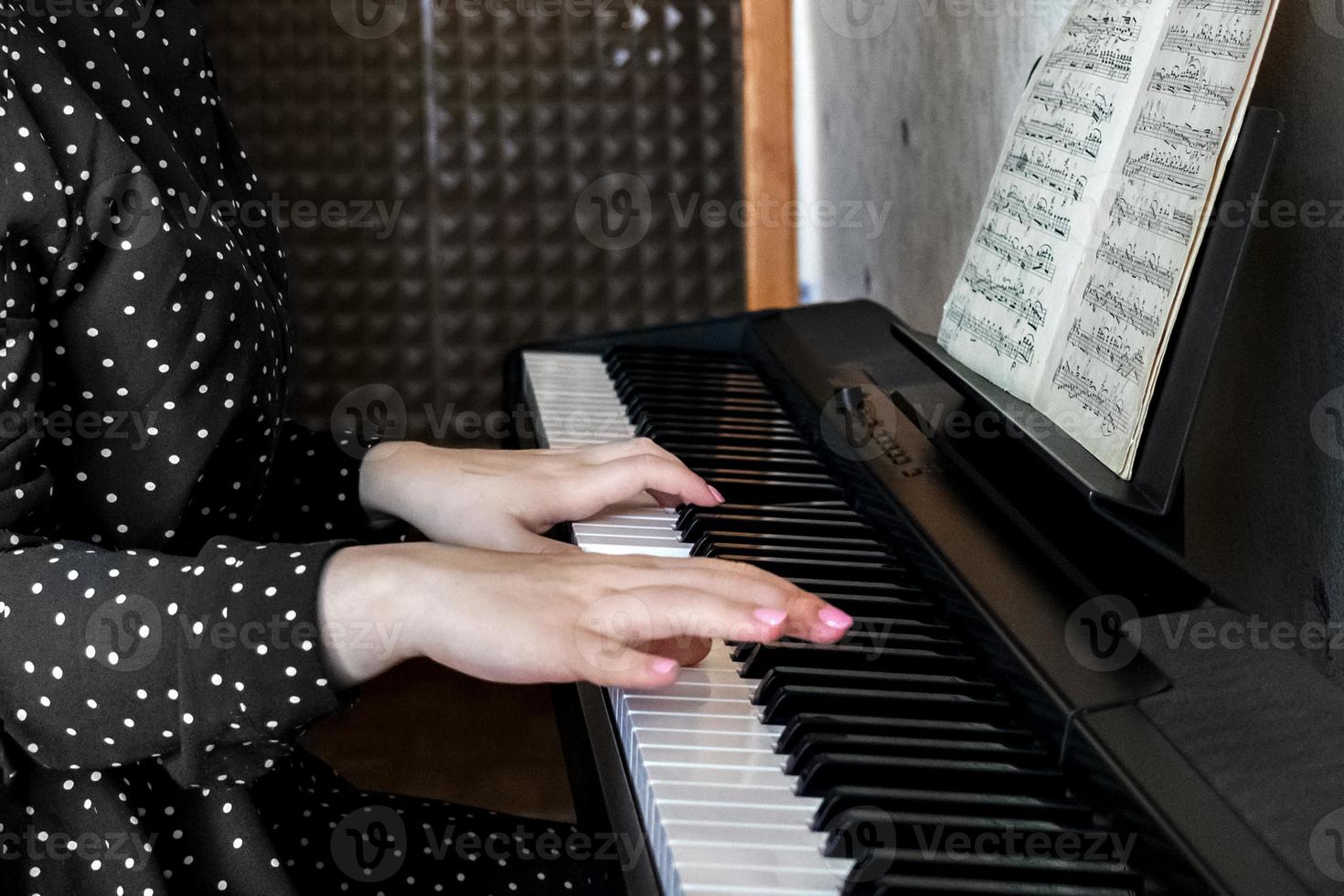 mani di una giovane pianista sui tasti di un sintetizzatore foto