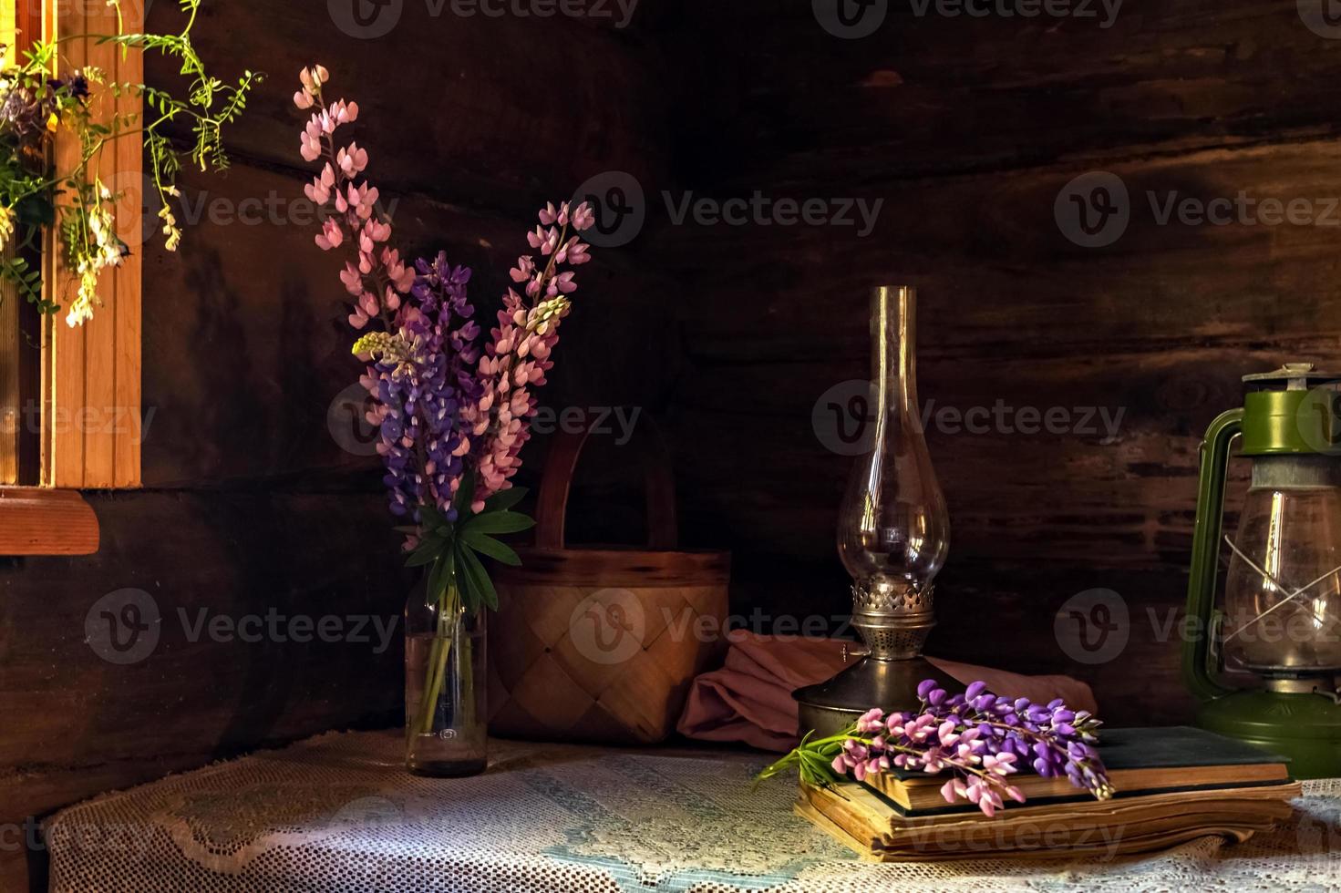 natura morta di oggetti vintage e un mazzo di lupini su un tavolo vicino alla finestra in una vecchia casa di paese. foto