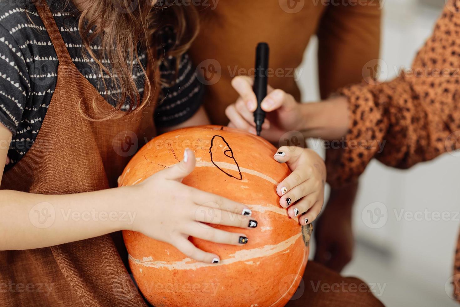 giovane ragazza seduta a un tavolo, decorare le zucche. vacanza di halloween e sfondo stile di vita familiare. bambina dipinge una zucca per halloween. messa a fuoco selettiva foto