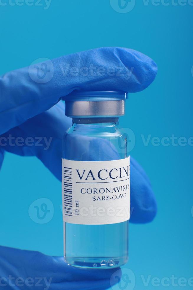 sviluppo e creazione di un vaccino contro il coronavirus covid-19 .vaccino contro il coronavirus in una bottiglia di vetro in mano al medico su sfondo blu. concetto di vaccino di lotta contro il coronavirus. foto
